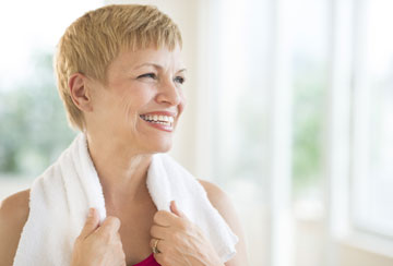 A smiling woman with a towel on her shoulders