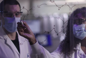 Two scientists writing on a board