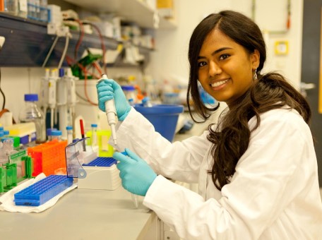 a person in a lab coat holding a pipette
