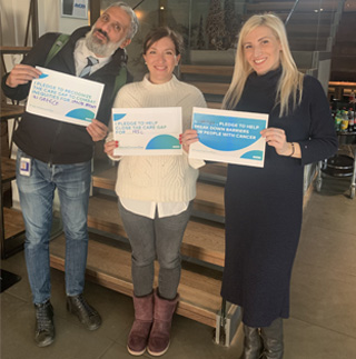 Three people smiling and holding a paper