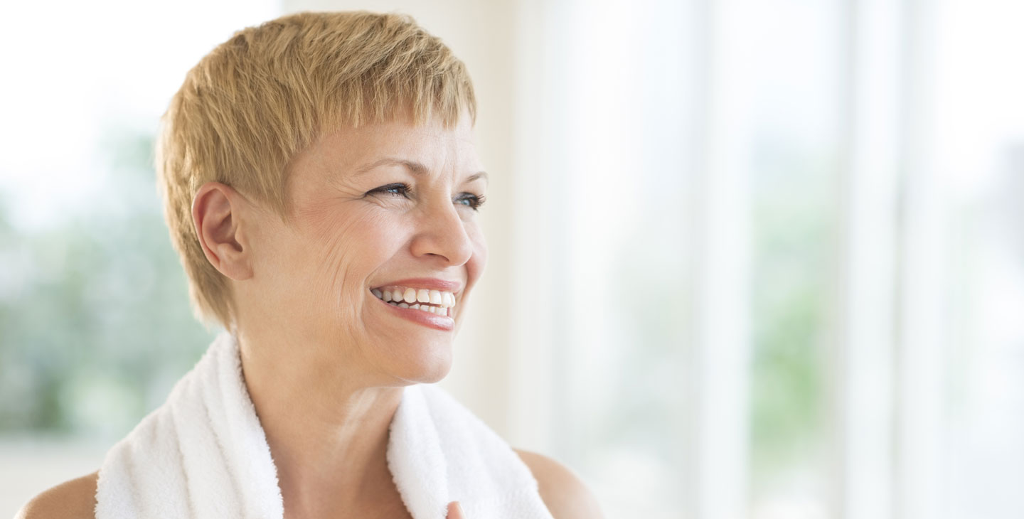 A smiling woman with a towel on her shoulders