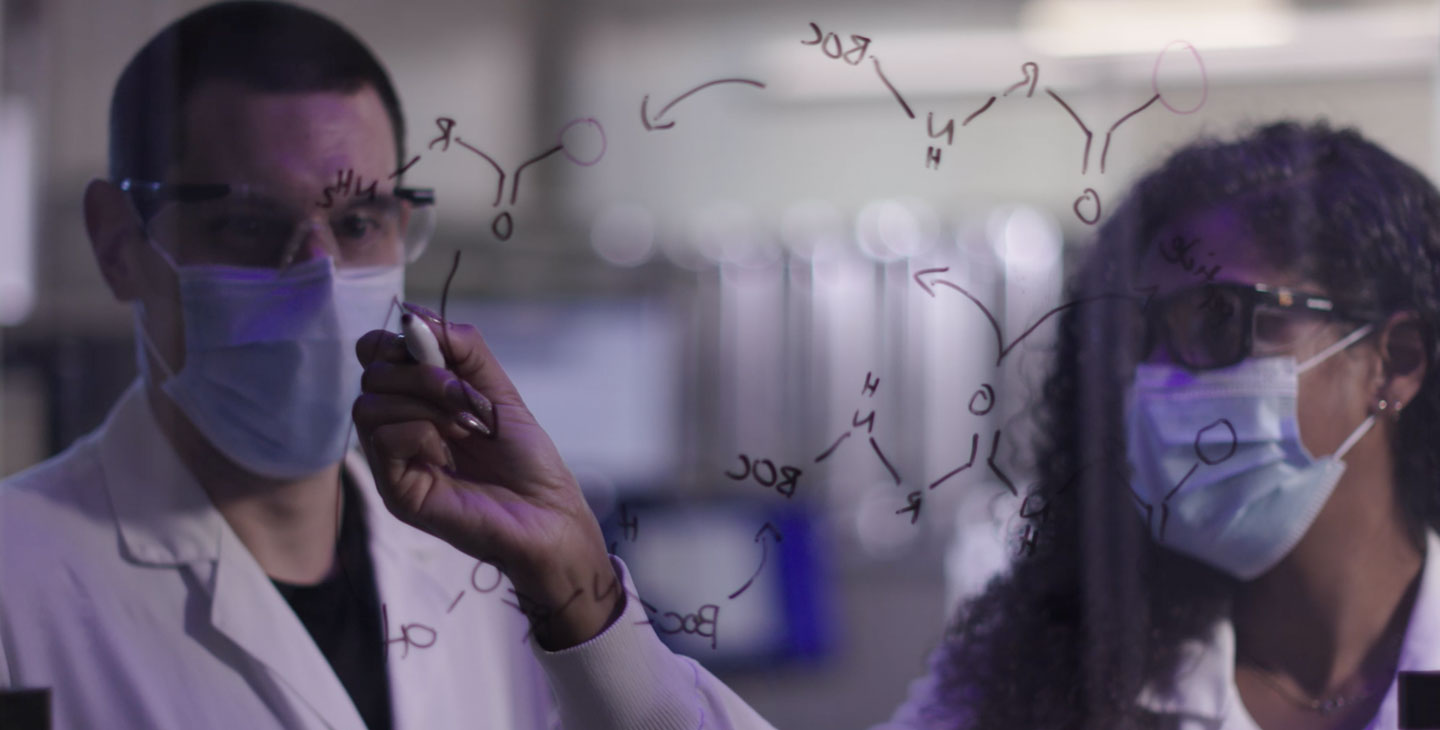 Two scientists writing on a board