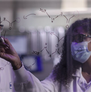 Two scientists writing on a board