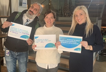 Three people smiling and holding a paper